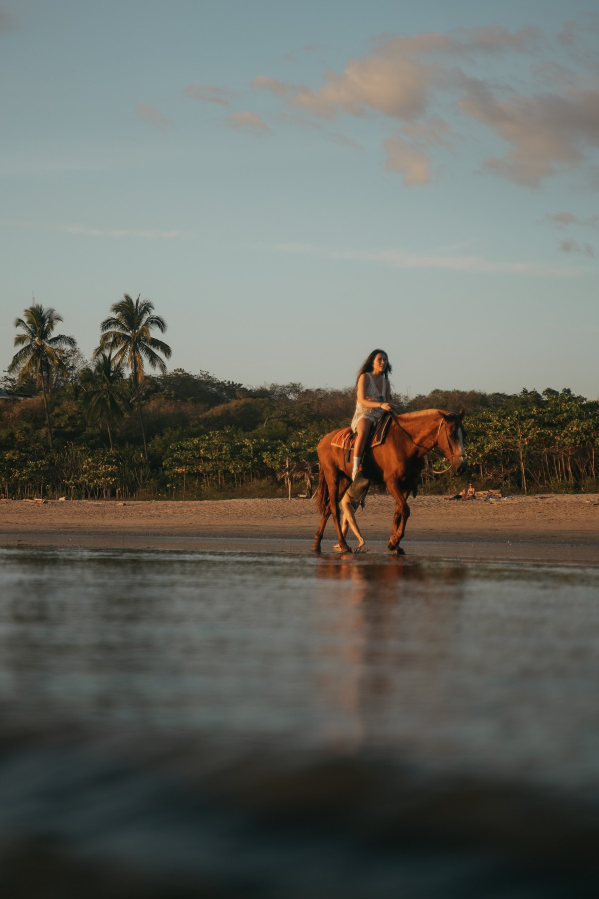 A woman running along the shoreline into the golden light at sunset