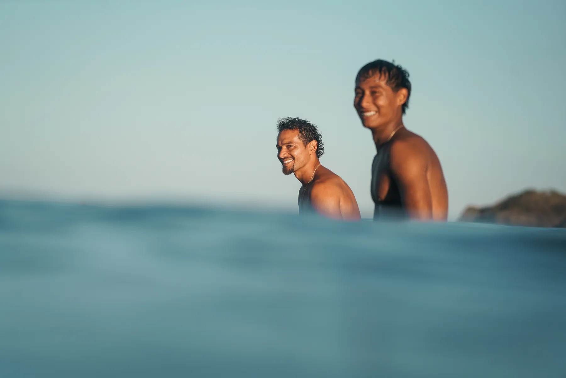 Two friends smiling in the water in golden light