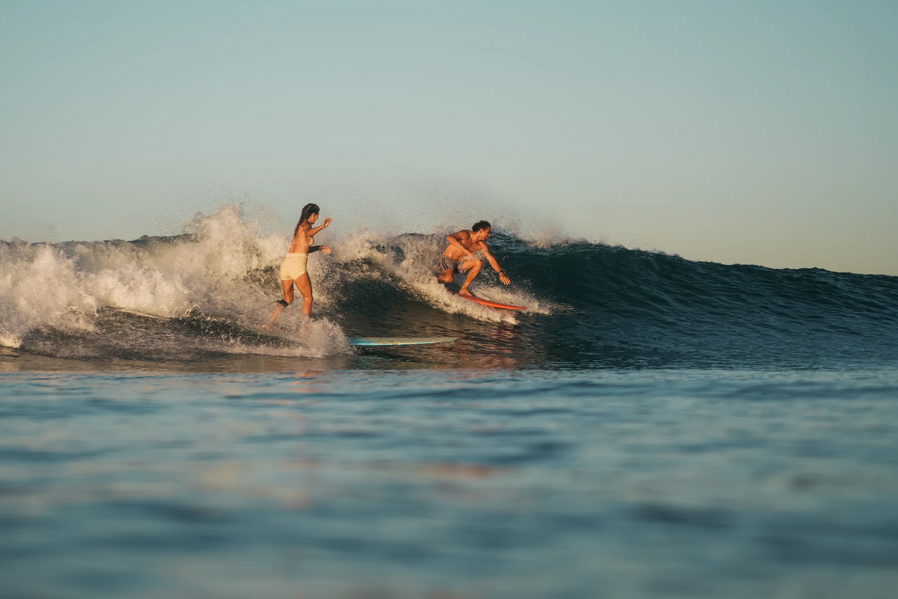 Two surfers sharing a wave at Playa Guiones, one leading the other