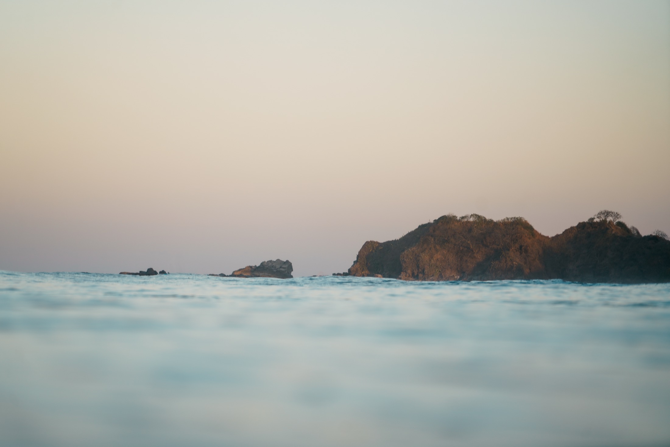 A rocky headland and calm sea at dusk near Nosara
